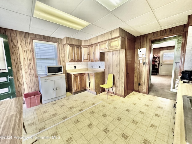 kitchen featuring light countertops, wood walls, light floors, and white microwave