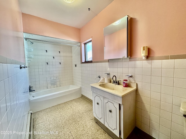 full bathroom with washtub / shower combination, wainscoting, vanity, and tile walls