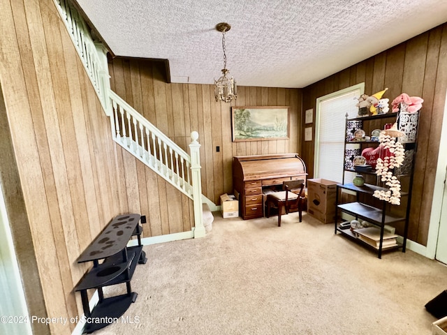 living area featuring stairs, a textured ceiling, carpet floors, wood walls, and a notable chandelier