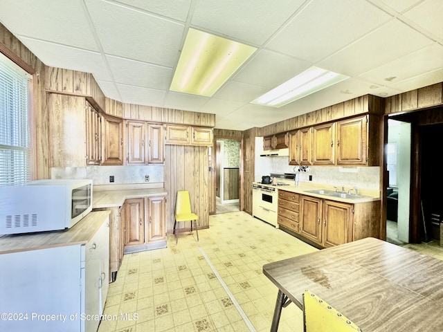 kitchen featuring white appliances, light countertops, and wood walls