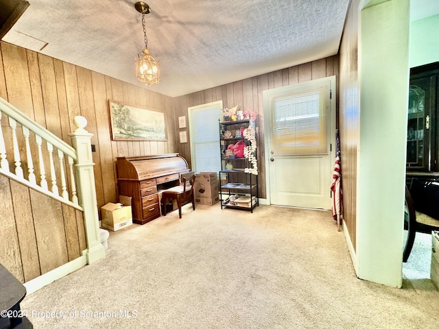 miscellaneous room with a textured ceiling, a notable chandelier, carpet floors, wood walls, and stairs