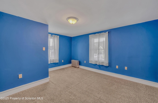 carpeted empty room with radiator heating unit and plenty of natural light