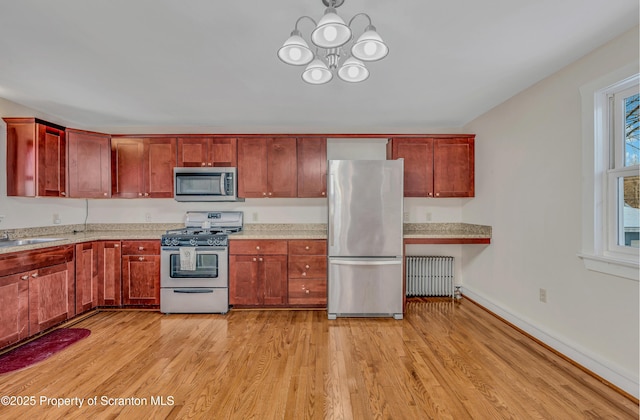 kitchen featuring stainless steel appliances, radiator, a chandelier, and light hardwood / wood-style floors