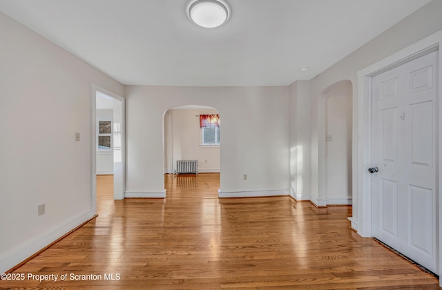 unfurnished room with radiator heating unit and light wood-type flooring