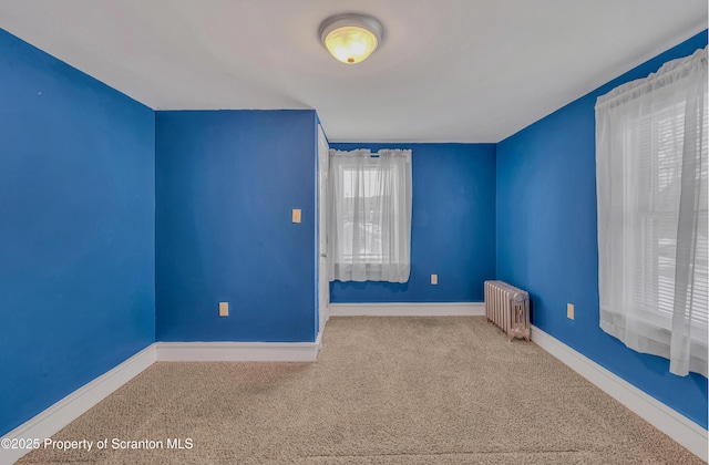 spare room with radiator heating unit and carpet flooring