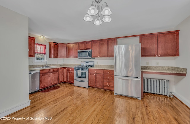 kitchen featuring appliances with stainless steel finishes, radiator, sink, light hardwood / wood-style floors, and an inviting chandelier