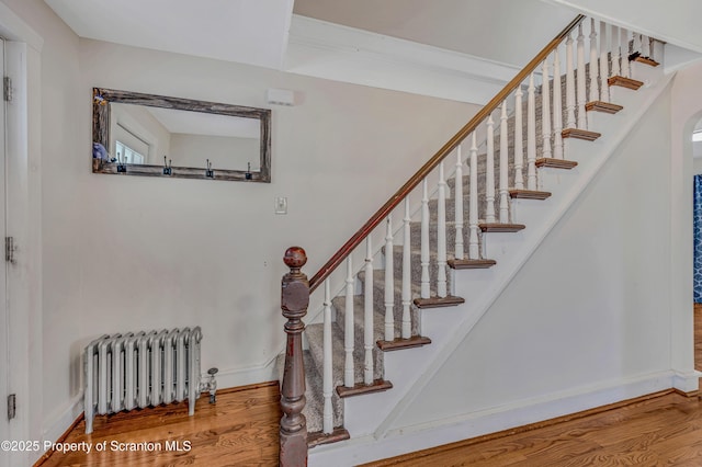 stairway with wood-type flooring and radiator heating unit