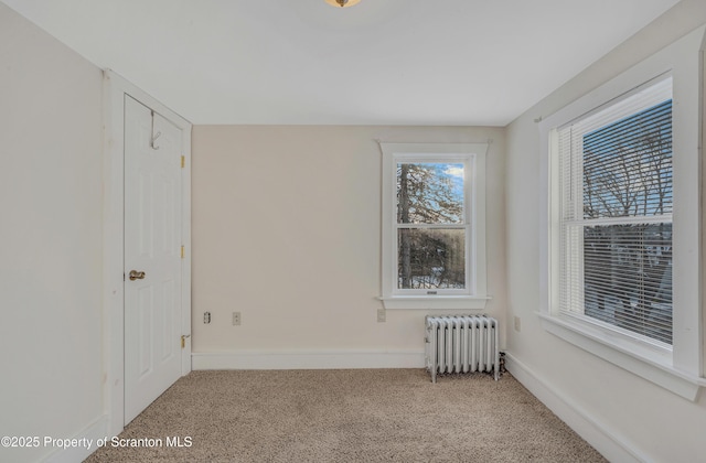 spare room featuring light colored carpet and radiator heating unit