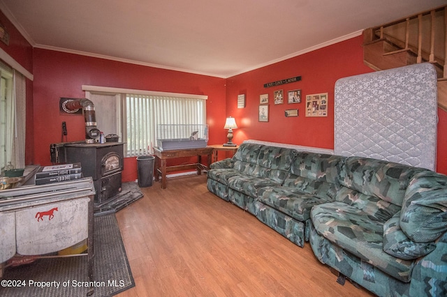 living room featuring wood-type flooring, a wood stove, and ornamental molding