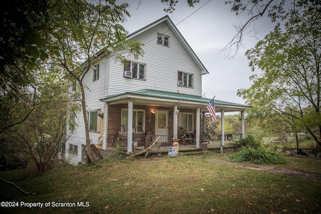 rear view of property with covered porch and a lawn