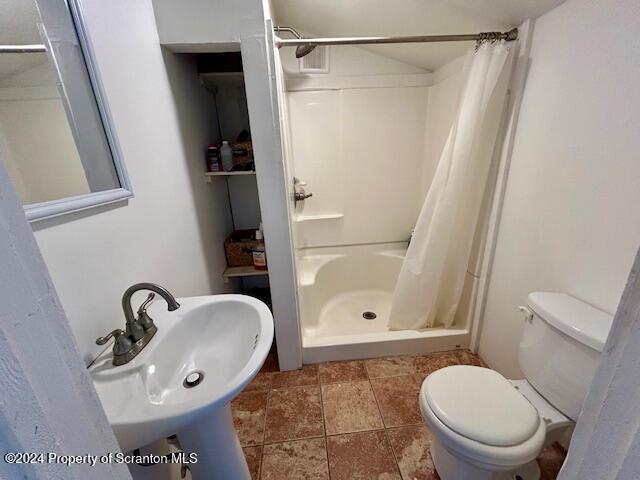 bathroom featuring curtained shower, sink, and toilet