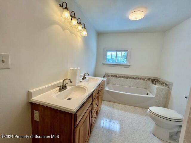 bathroom with a bathing tub, vanity, toilet, and tile patterned flooring