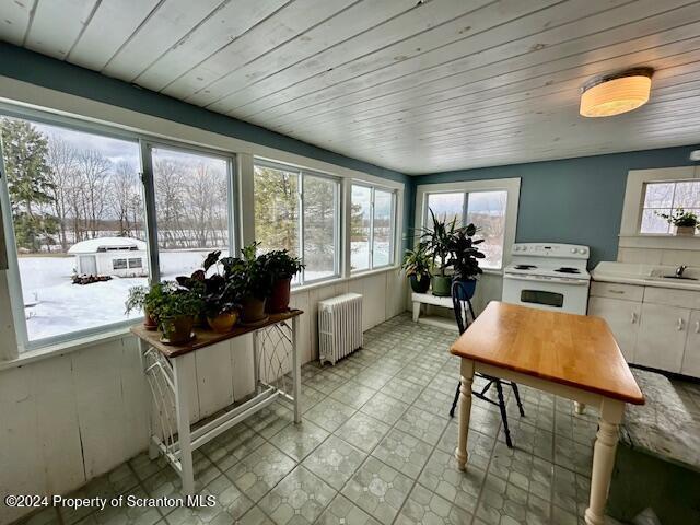 sunroom / solarium featuring radiator heating unit, a wealth of natural light, and sink