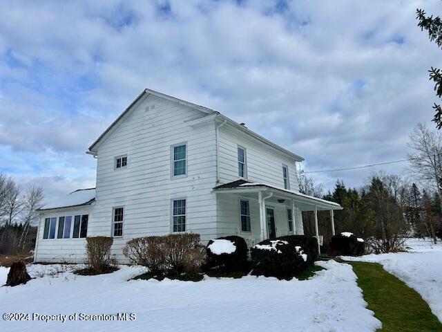 view of snow covered exterior featuring a porch