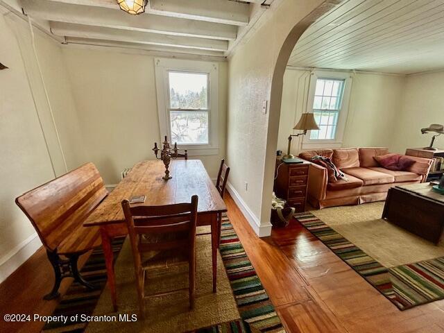 dining area with beam ceiling and wood-type flooring