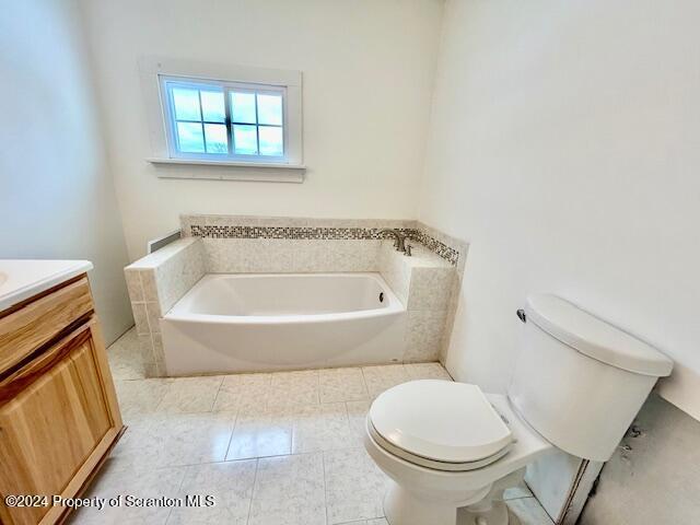 bathroom featuring tile patterned flooring, a washtub, toilet, and vanity