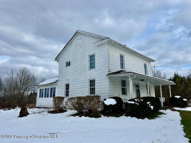 snow covered property featuring a porch