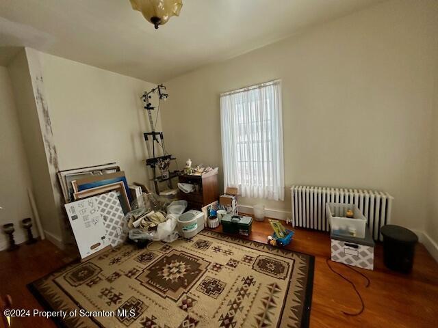 interior space with wood-type flooring and radiator heating unit