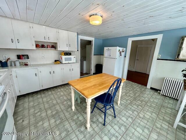 kitchen with radiator, white cabinetry, wood ceiling, and white appliances