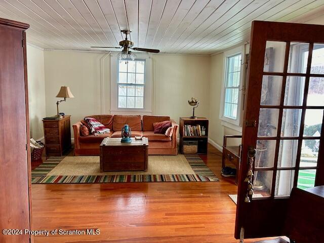 living room with light hardwood / wood-style floors, ceiling fan, and wooden ceiling