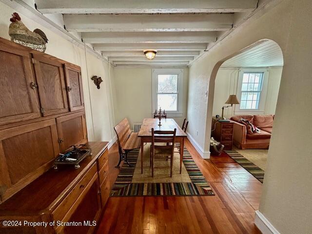 dining room with beam ceiling and dark wood-type flooring