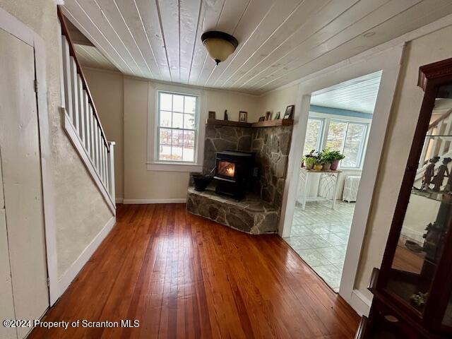 unfurnished living room featuring hardwood / wood-style floors, plenty of natural light, wood ceiling, and radiator heating unit