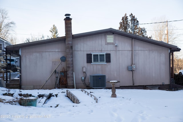 snow covered back of property featuring central AC