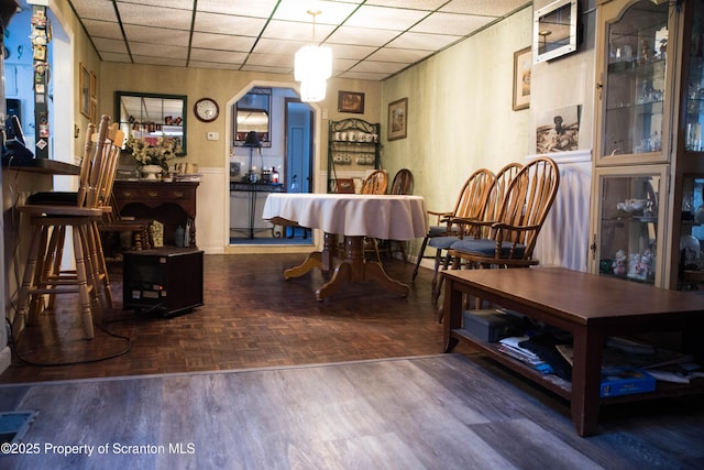 dining area with parquet flooring and a drop ceiling