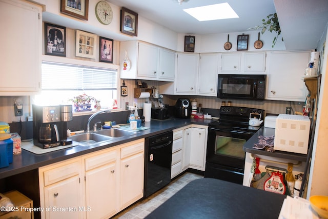 kitchen with white cabinetry, sink, a skylight, and black appliances