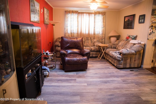 sitting room featuring ceiling fan, ornamental molding, and light wood-type flooring