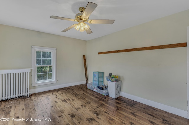 empty room featuring radiator heating unit, hardwood / wood-style flooring, and ceiling fan