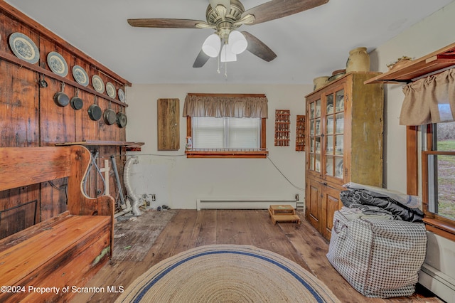 misc room with hardwood / wood-style floors, ceiling fan, and a baseboard heating unit