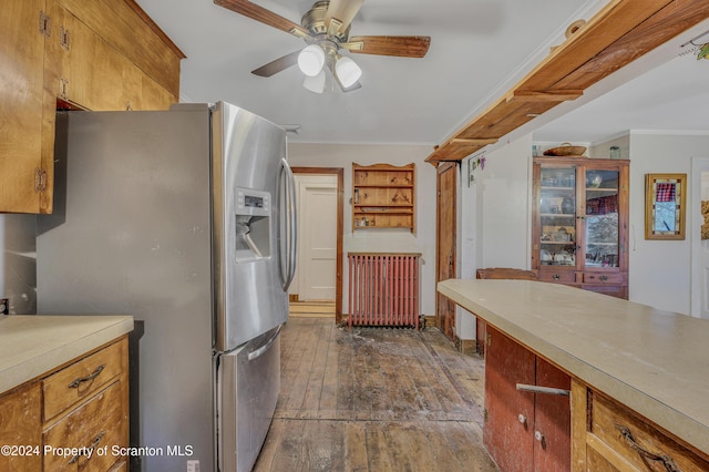 kitchen featuring radiator, ceiling fan, dark wood-type flooring, stainless steel fridge with ice dispenser, and ornamental molding