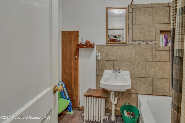 bathroom featuring backsplash, a tub to relax in, sink, tile walls, and radiator heating unit