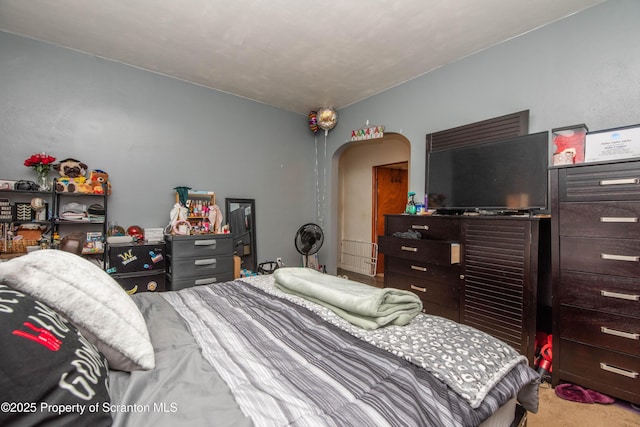 bedroom featuring arched walkways and carpet