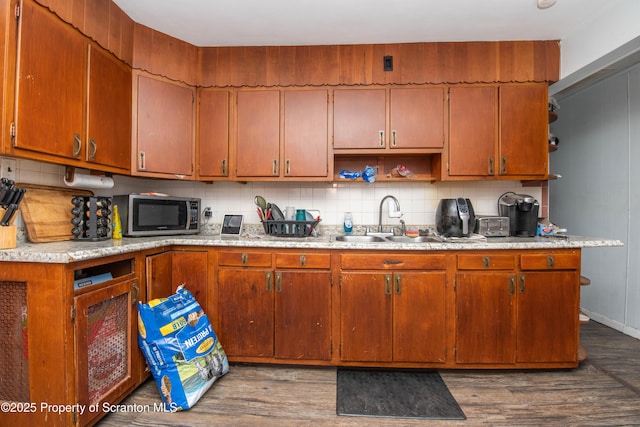 kitchen with stainless steel microwave, backsplash, wood finished floors, and a sink