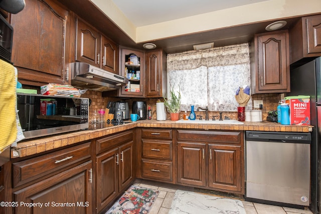 kitchen featuring under cabinet range hood, tasteful backsplash, stainless steel appliances, and a sink