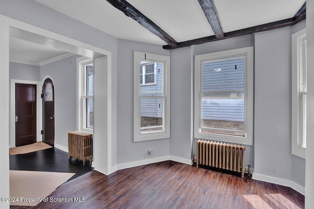 empty room with beamed ceiling, dark hardwood / wood-style floors, crown molding, and radiator