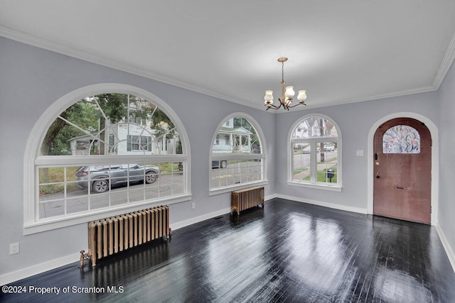 unfurnished dining area with radiator heating unit, dark hardwood / wood-style flooring, an inviting chandelier, and ornamental molding