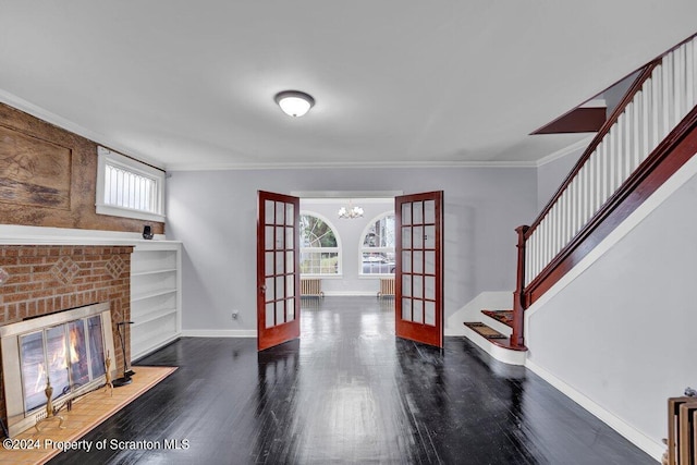 living room with built in shelves, french doors, dark hardwood / wood-style floors, a notable chandelier, and ornamental molding