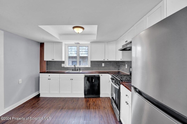 kitchen featuring a raised ceiling, backsplash, white cabinetry, and appliances with stainless steel finishes