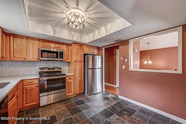 kitchen with appliances with stainless steel finishes, light countertops, backsplash, baseboards, and a notable chandelier