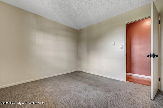 carpeted spare room featuring a textured ceiling and baseboards