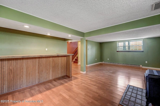 bar featuring a baseboard radiator, wood finished floors, visible vents, and a textured ceiling