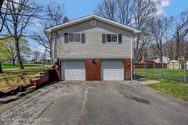 view of side of property with driveway, fence, a lawn, and an attached garage