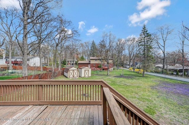 wooden terrace featuring an outdoor structure, a residential view, a storage unit, a lawn, and a fenced backyard