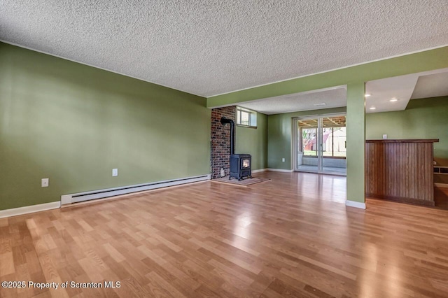 unfurnished living room with a wood stove, baseboards, a textured ceiling, wood finished floors, and a baseboard radiator