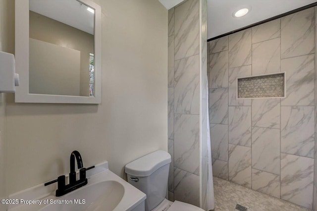 bathroom with recessed lighting, toilet, a tile shower, and vanity