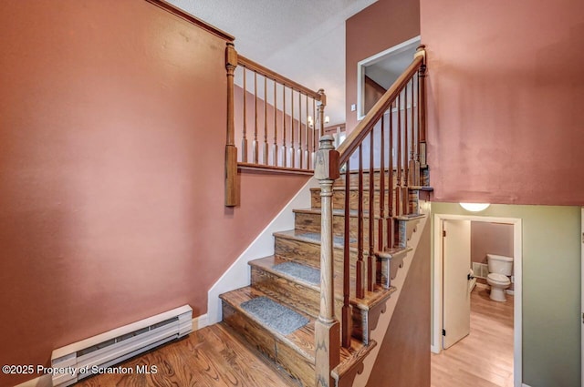 staircase featuring baseboard heating and wood finished floors
