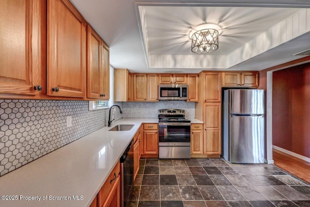 kitchen with appliances with stainless steel finishes, light countertops, brown cabinets, backsplash, and a sink